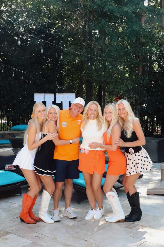 A family with four siblings dressed in UT orange hugging their mom and dad.