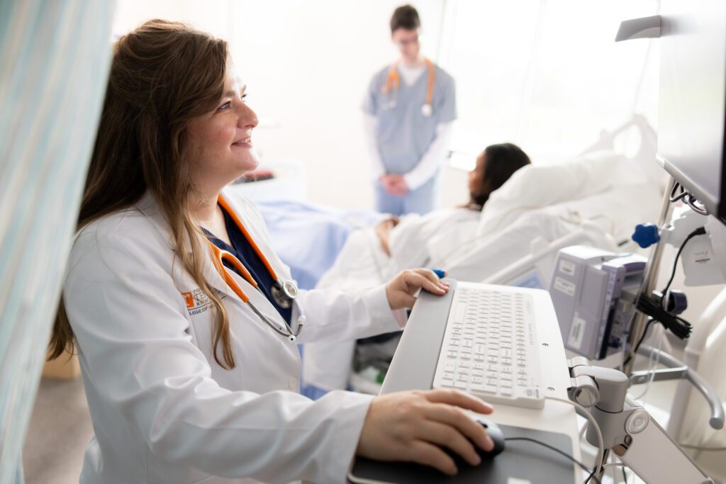PhD student is seen on a computer in a clinical lab space.