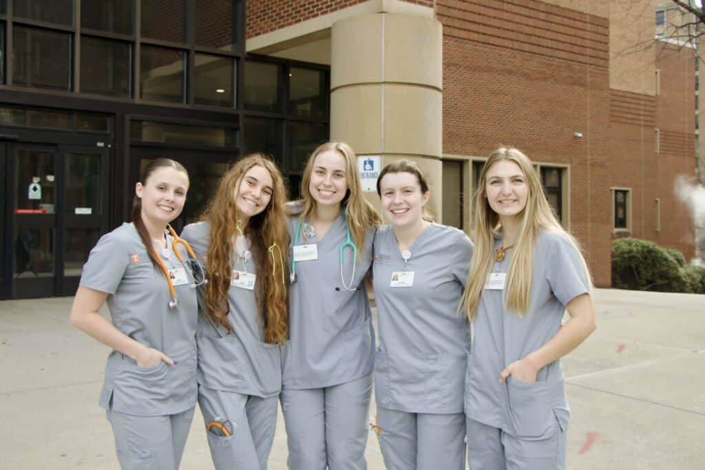 Five nursing students in scrubs standing outside of the library during the Great Expectations Conference.